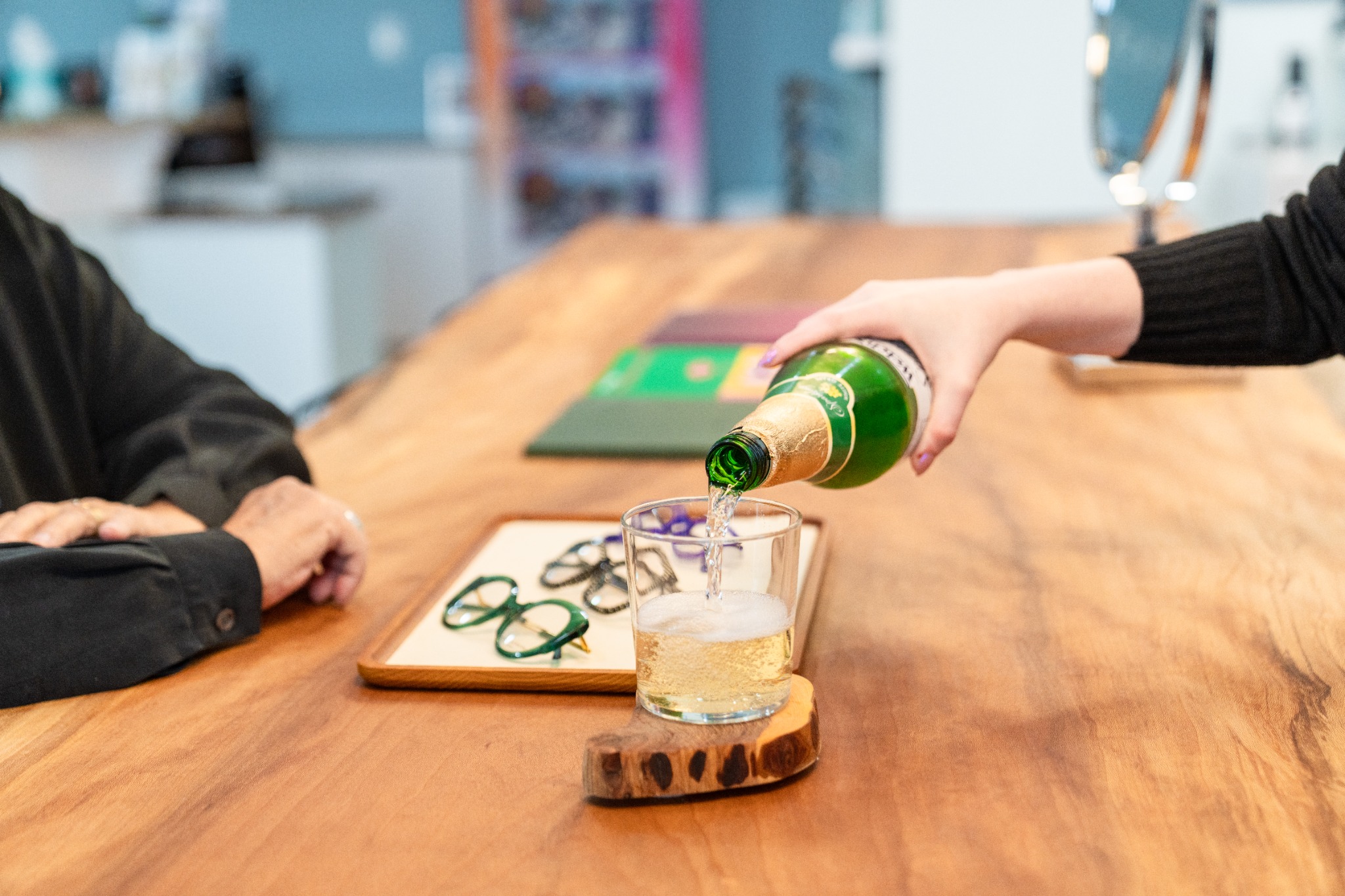 A drink being poured beside a tray of selected eyeglass frames at Bright Side Optical