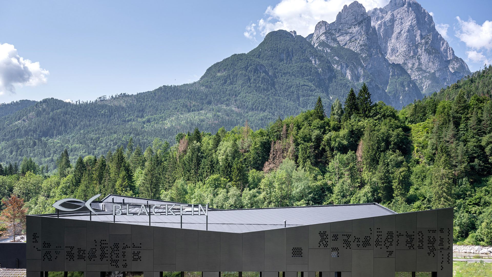 Blackfin’s Black Shelter factory beneath forested mountains and the rocky peaks of the Italian Dolomites