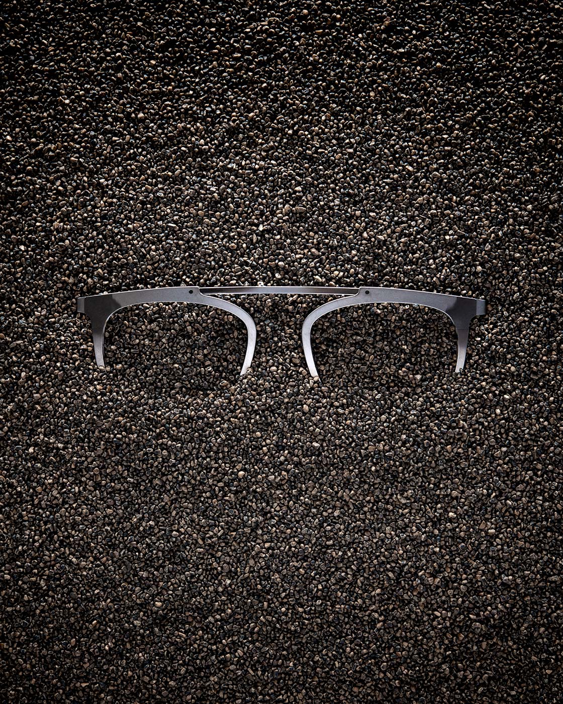 An unfinished Blackfin titanium frame front showing the clean-cut bridge and lens outlines against a textured dark surface