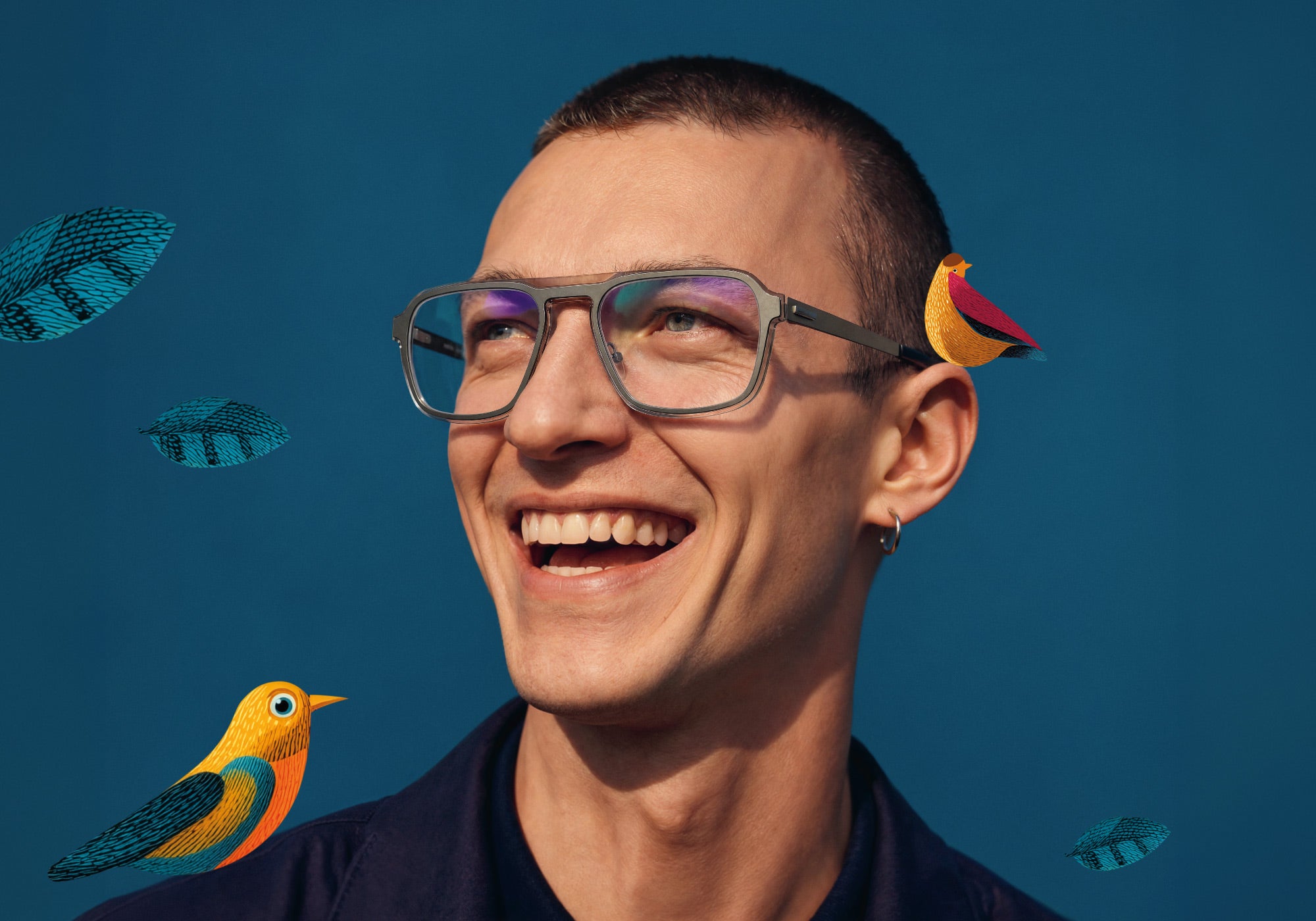 Smiling man wearing gray Morel optical glasses in an official campaign portrait against teal with colorful illustrated birds