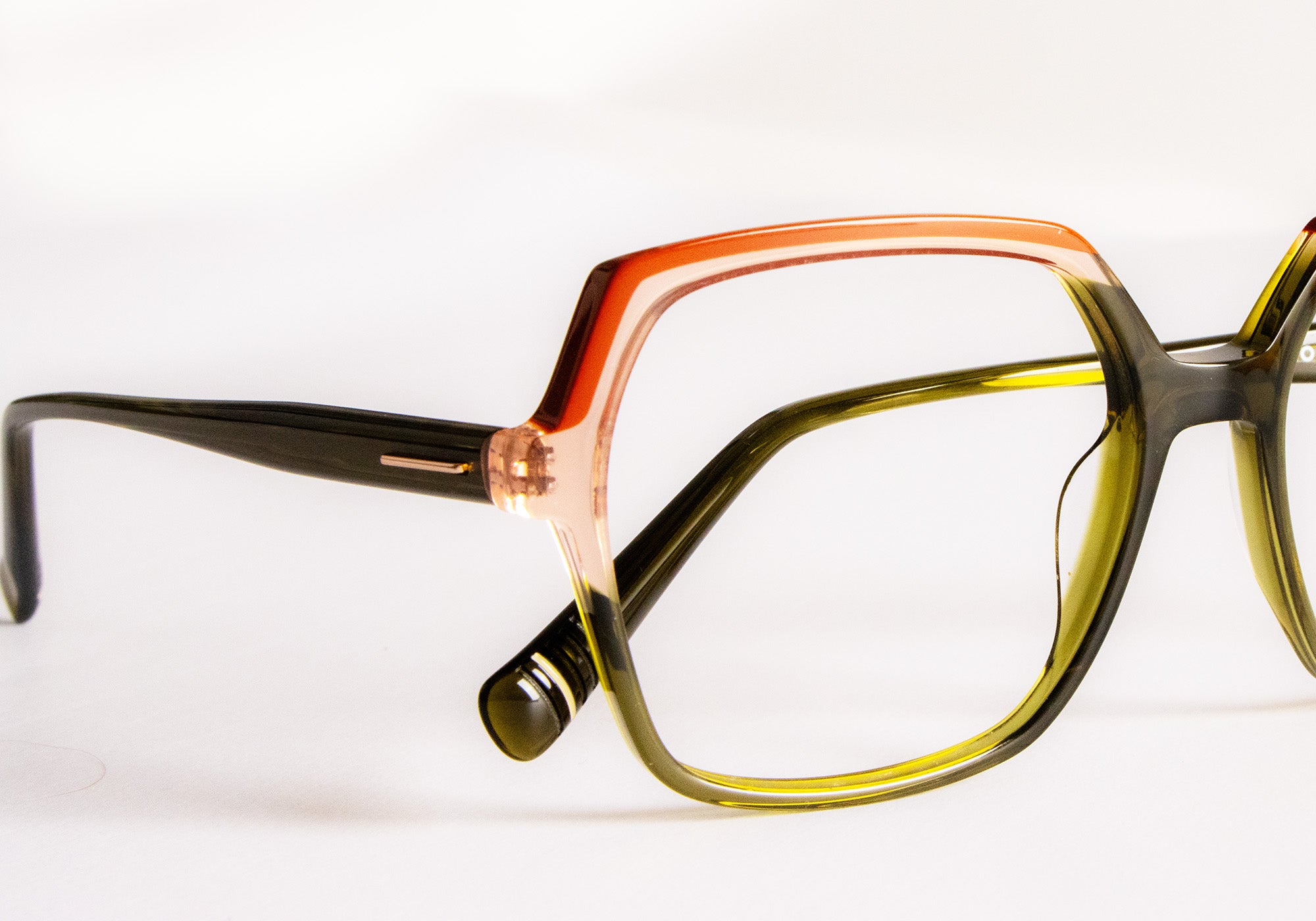 Close-up of Morel’s hinge and temple connection on translucent olive, pink, and orange acetate eyewear