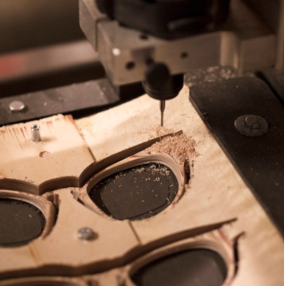 A precision milling tool cutting a Nina Mûr frame from layered wood in the workshop