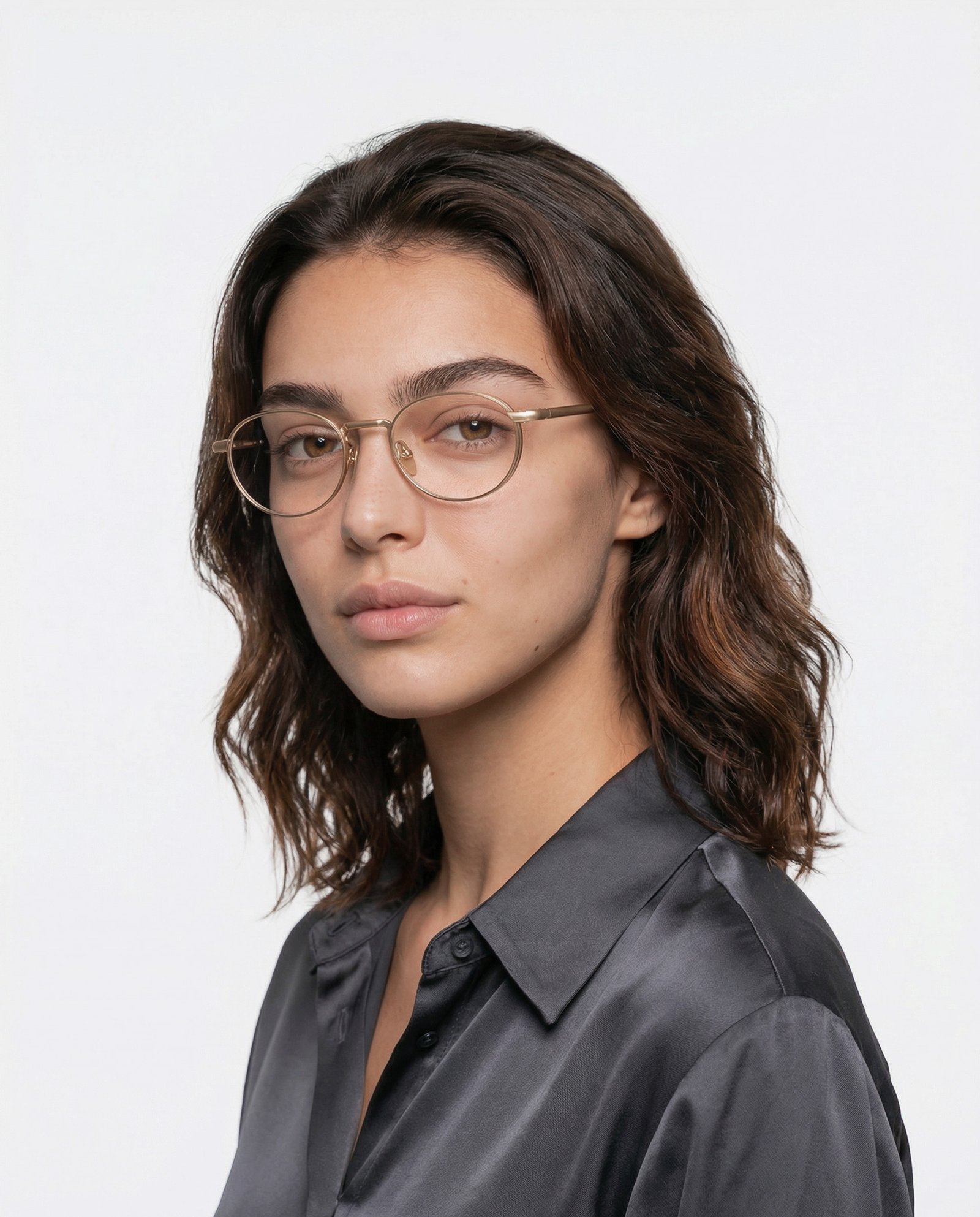 UDM FRAME 55 campaign portrait of a woman wearing fine gold-toned rounded optical glasses with a dark collared shirt