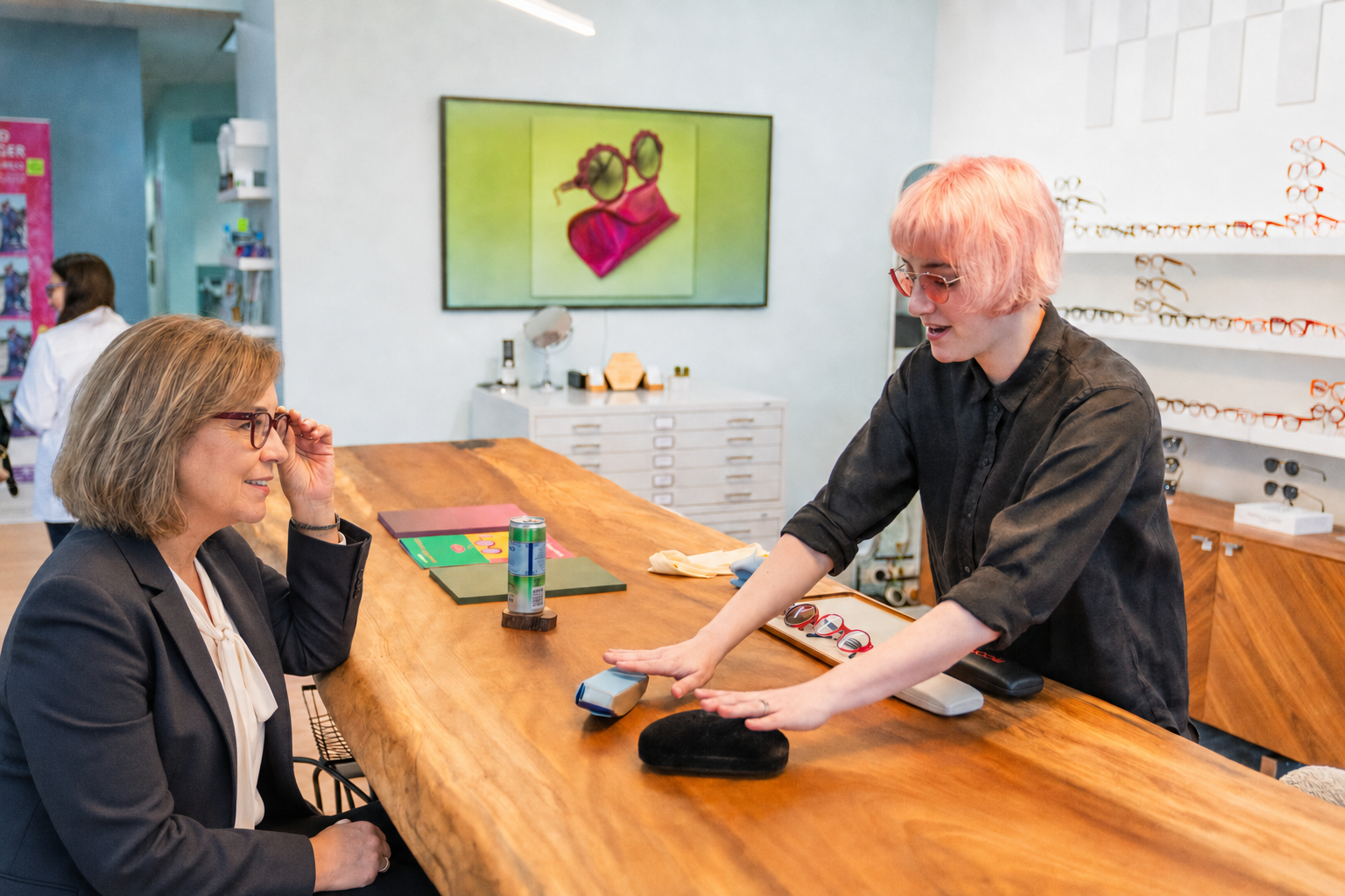 A stylist explaining frame choices to a client during a seated eyewear appointment